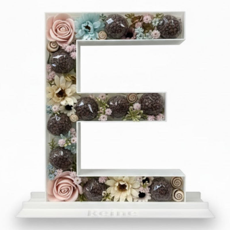Decorative letter 'E' made of flowers and plants 