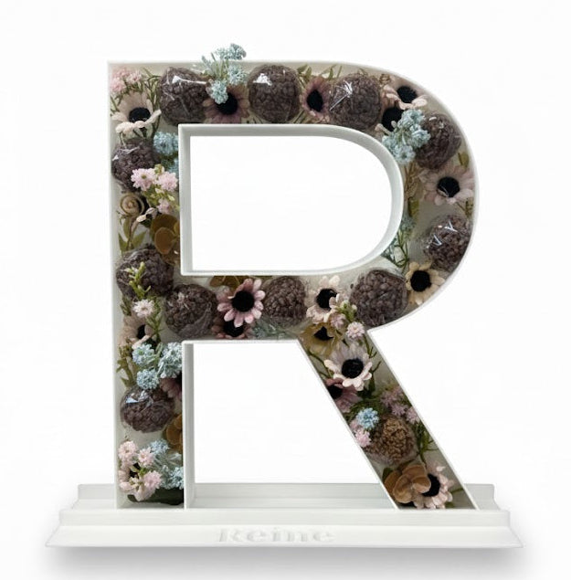 Decorative letter 'R' made of natural elements on a white background